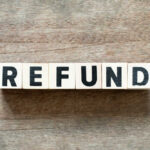 Wooden blocks spelling the word 'REFUND' on a wooden surface