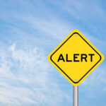 Yellow alert sign against a blue sky