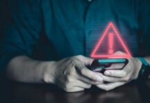 Person holding phone with warning symbol displayed.