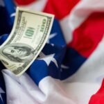 A hundred dollar bill resting on an American flag