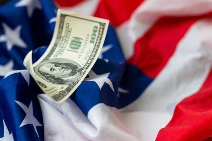 shutterstock_2401408751.jpg A hundred dollar bill resting on an American flag