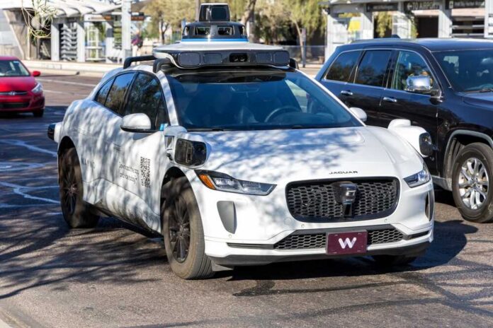 A white autonomous Jaguar I-PACE parked in an urban setting