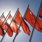 Chinese flags waving under a clear sky.