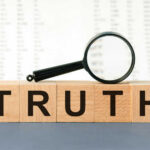 Wooden blocks spelling truth with magnifying glass