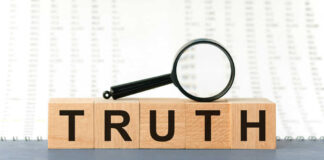 Wooden blocks spelling truth with magnifying glass