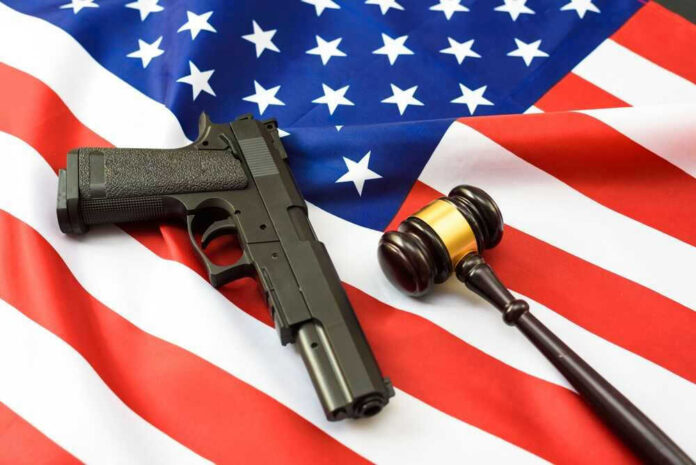 shutterstock_2214433687.jpg Gun and gavel on a U.S. flag.