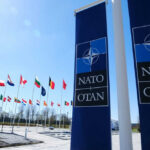 NATO flags flying under clear blue sky