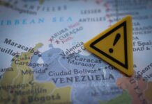 A close-up of a map showing Venezuela with a yellow warning sign