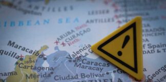 A close-up of a map showing Venezuela with a yellow warning sign
