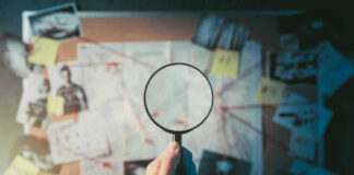 Magnifying glass over investigation board with photos and strings.