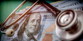 A stethoscope resting on a stack of hundred-dollar bills