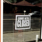 Closed sign hanging on a glass door