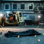 Police investigation at a crime scene with a covered body and evidence markers