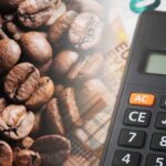Close-up of coffee beans next to a calculator on a financial document