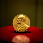 A gold Nobel Prize medal displayed on a red pedestal