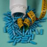 Spilled blue capsules and a measuring tape on a turquoise background