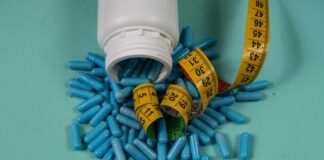 Spilled blue capsules and a measuring tape on a turquoise background