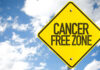 A yellow warning sign that reads 'CANCER FREE ZONE' against a blue sky
