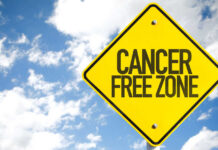 A yellow warning sign that reads 'CANCER FREE ZONE' against a blue sky