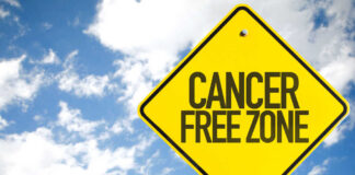 A yellow warning sign that reads 'CANCER FREE ZONE' against a blue sky