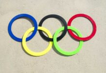 Colorful Olympic rings arranged on sandy surface