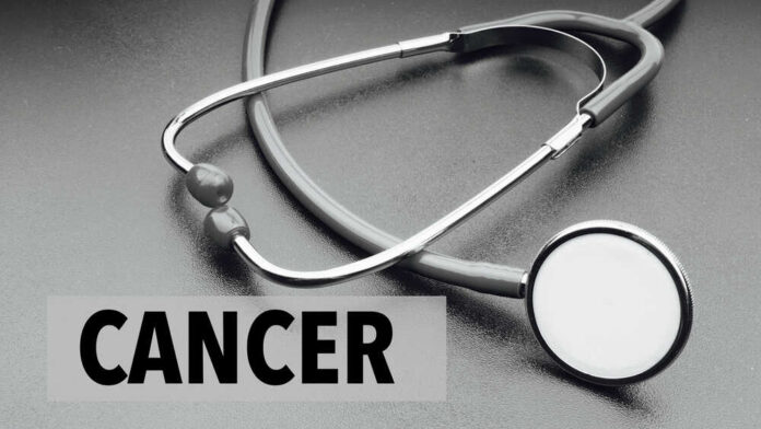 A stethoscope on a dark surface with the word 'CANCER' prominently displayed