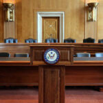 Empty Senate chamber with a wooden podium and chairs