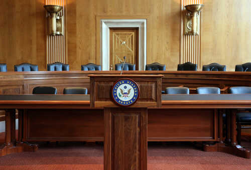 Empty Senate chamber with a wooden podium and chairs