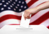 Hand dropping ballot into box, American flag background.