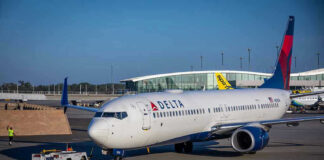 Delta airplane being towed at airport terminal gate.
