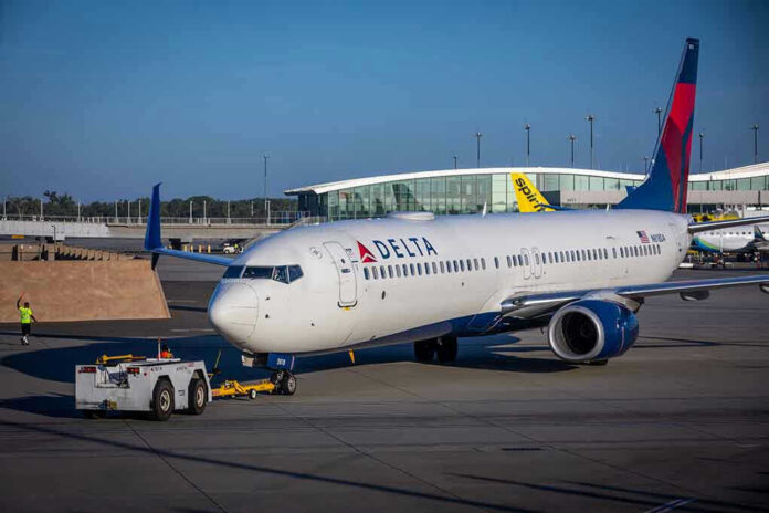 2121460637 Delta airplane being towed at airport terminal gate.