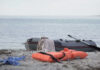 An inflatable boat on the beach with a life jacket and clothes nearby