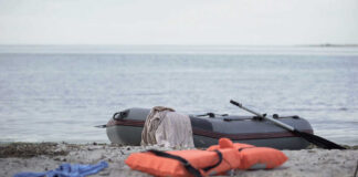 An inflatable boat on the beach with a life jacket and clothes nearby