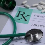 A prescription pad with a stethoscope and pills nearby