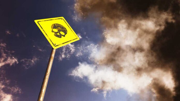 A yellow warning sign with a skull symbol against a cloudy sky