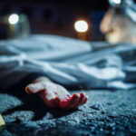 Crime scene with covered body and hand exposed.