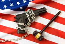 A handgun chained on an American flag with a gavel beside it