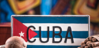 A decorative Cuban license plate with a maraca and a bundle of cigars