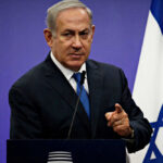 Netanyahu speaking at podium with Israeli flag.