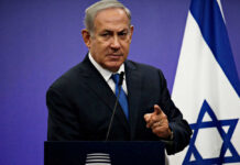 Netanyahu speaking at podium with Israeli flag.