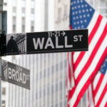 Wall Street and Broad Street signs with American flags in background