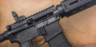 Black rifle on wooden surface close up