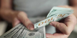 Hands holding stack of one hundred dollar bills