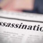 Close-up of a newspaper headline reading 'Assassination'
