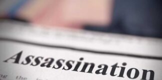 Close-up of a newspaper headline reading 'Assassination'