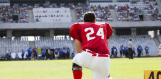 Football player in a red jersey kneeling on the field