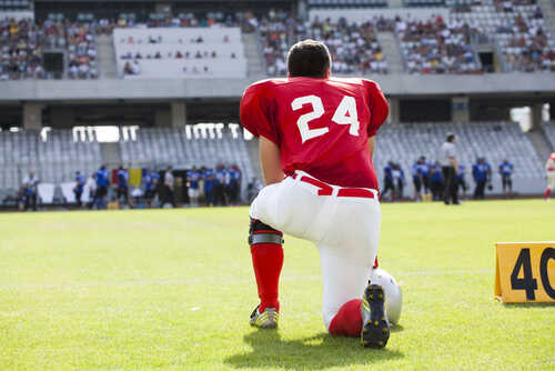 American,Football,Player Football player in a red jersey kneeling on the field