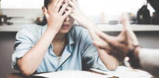 Stressed woman with hands on face at a desk.